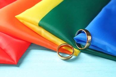 Photo of Wedding rings and rainbow flag on wooden table. Gay marriage