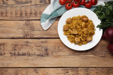 Delicious rice with chicken served on wooden table, flat lay. Space for text