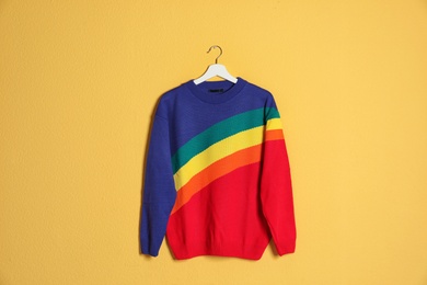 Hanger with stylish sweater on color background