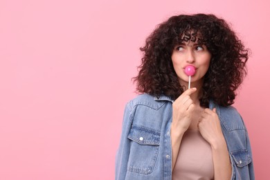 Beautiful woman with lollipop on pink background, space for text