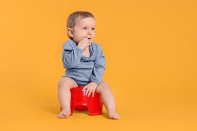 Photo of Little child sitting on baby potty against yellow background. Space for text