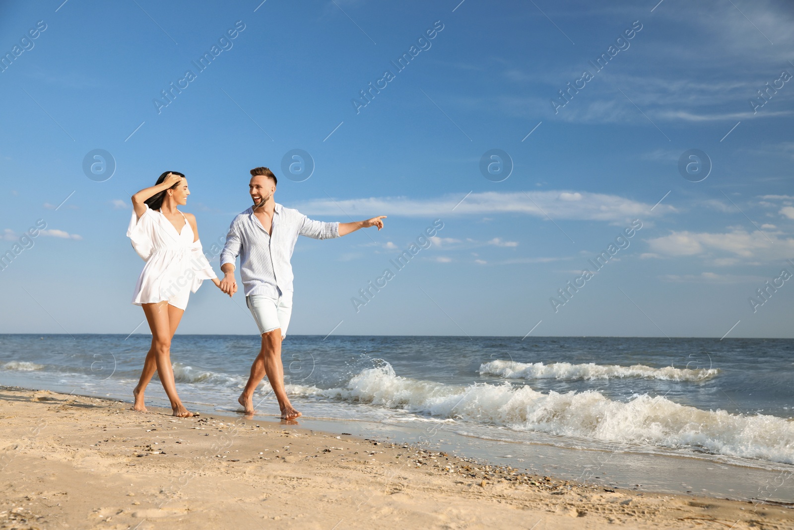 Photo of Happy young couple walking at beach on sunny day