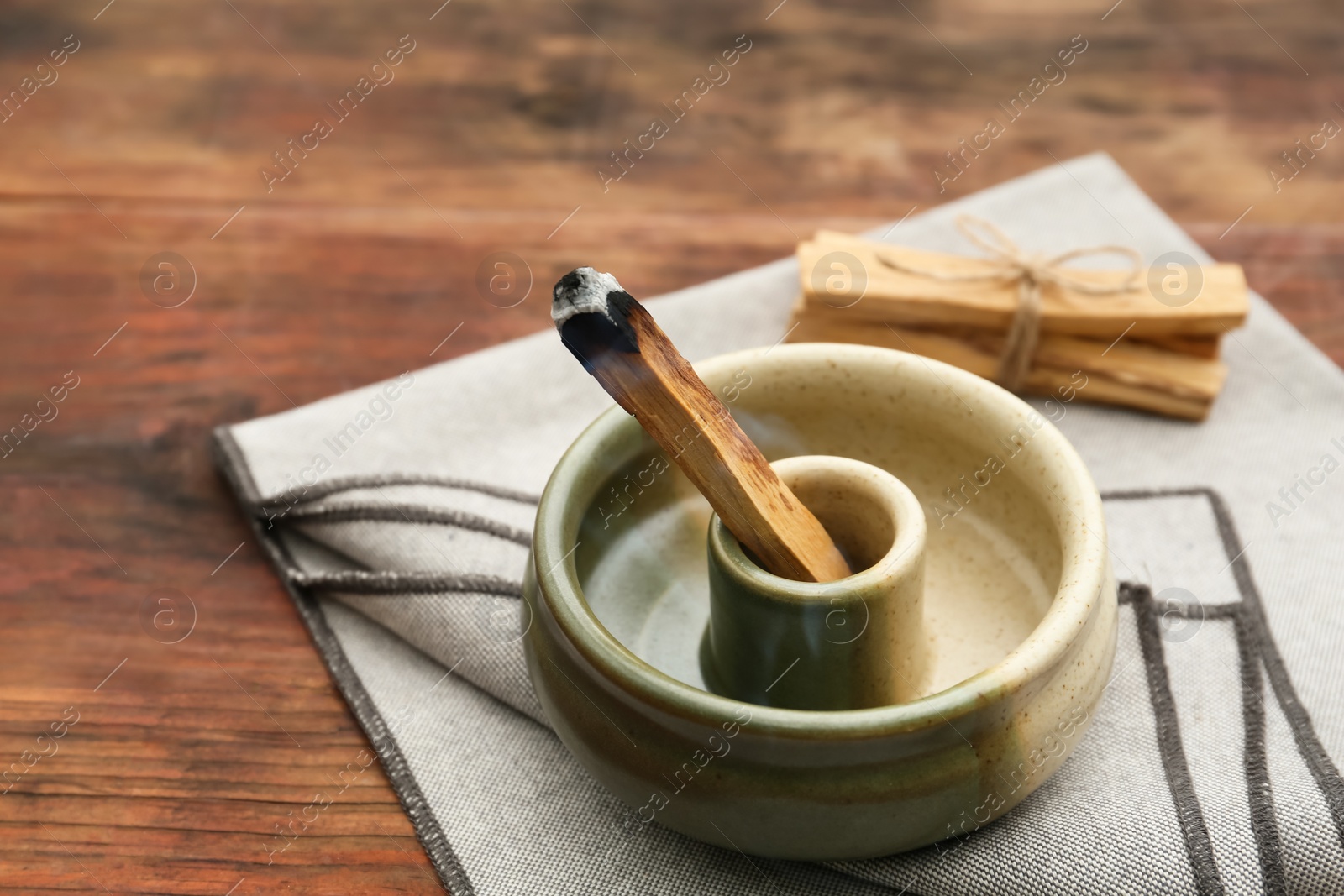 Photo of Palo Santo stick smoldering in holder on wooden table