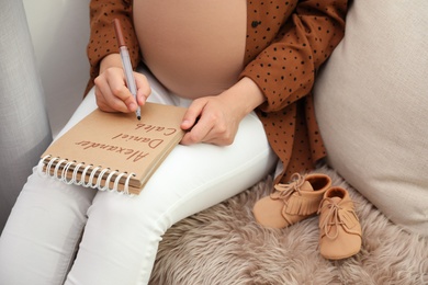 Pregnant woman writing baby names list, closeup