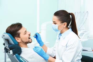 Photo of Professional dentist working with patient in modern clinic