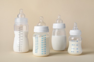 Photo of Feeding bottles with baby formula on beige background