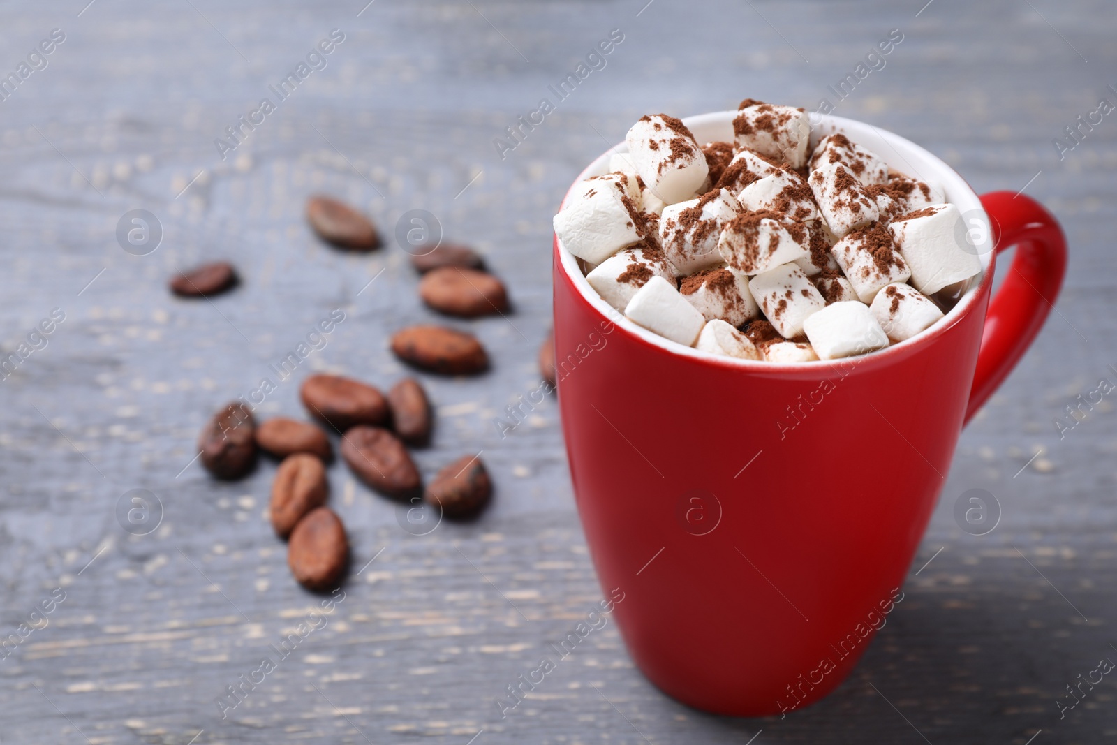 Photo of Cup of tasty cocoa with marshmallows and beans on grey wooden table. Space for text