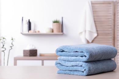 Photo of Stack of fresh towels on table in bathroom. Space for text