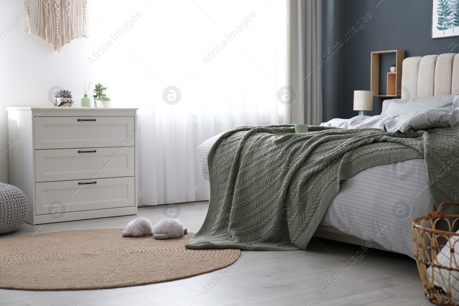 Photo of Comfortable bed with knitted green plaid in stylish room interior