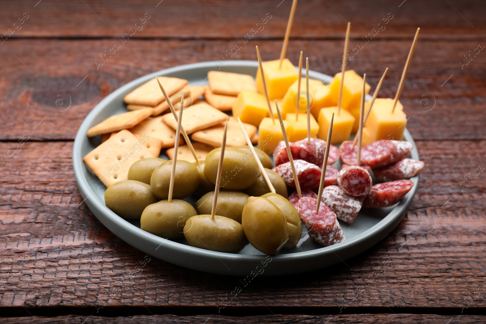 Photo of Toothpick appetizers. Olives, pieces of sausage and cheese on wooden table