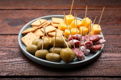 Toothpick appetizers. Olives, pieces of sausage and cheese on wooden table