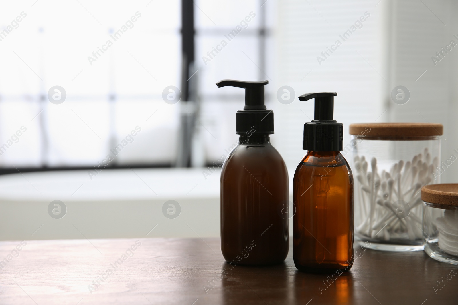 Photo of Dispensers of liquid soap on wooden table in bathroom. Space for text