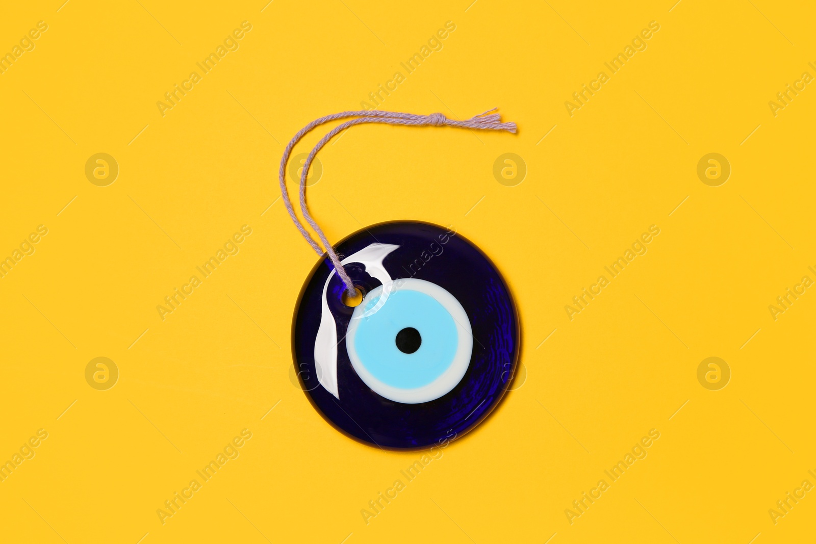 Photo of Evil eye amulet on orange background, top view