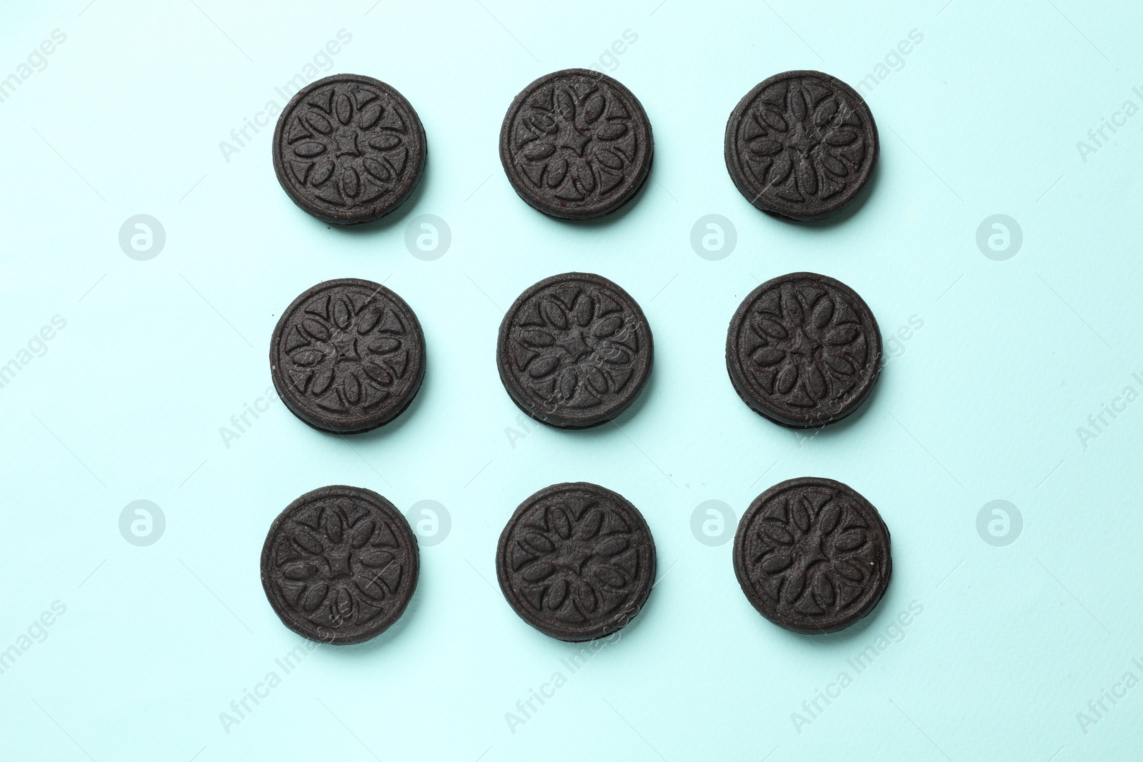 Photo of Tasty sweet sandwich cookies on light blue background, flat lay