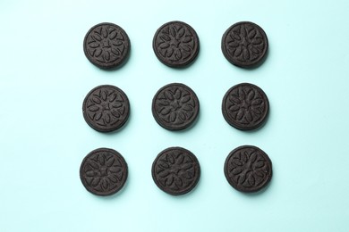 Photo of Tasty sweet sandwich cookies on light blue background, flat lay