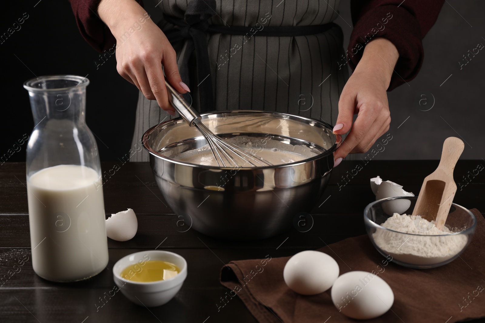 Photo of Woman making dough with whisk in bowl at table, closeup