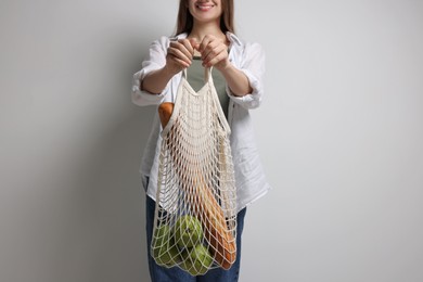 Woman with eco bag full of products on white background