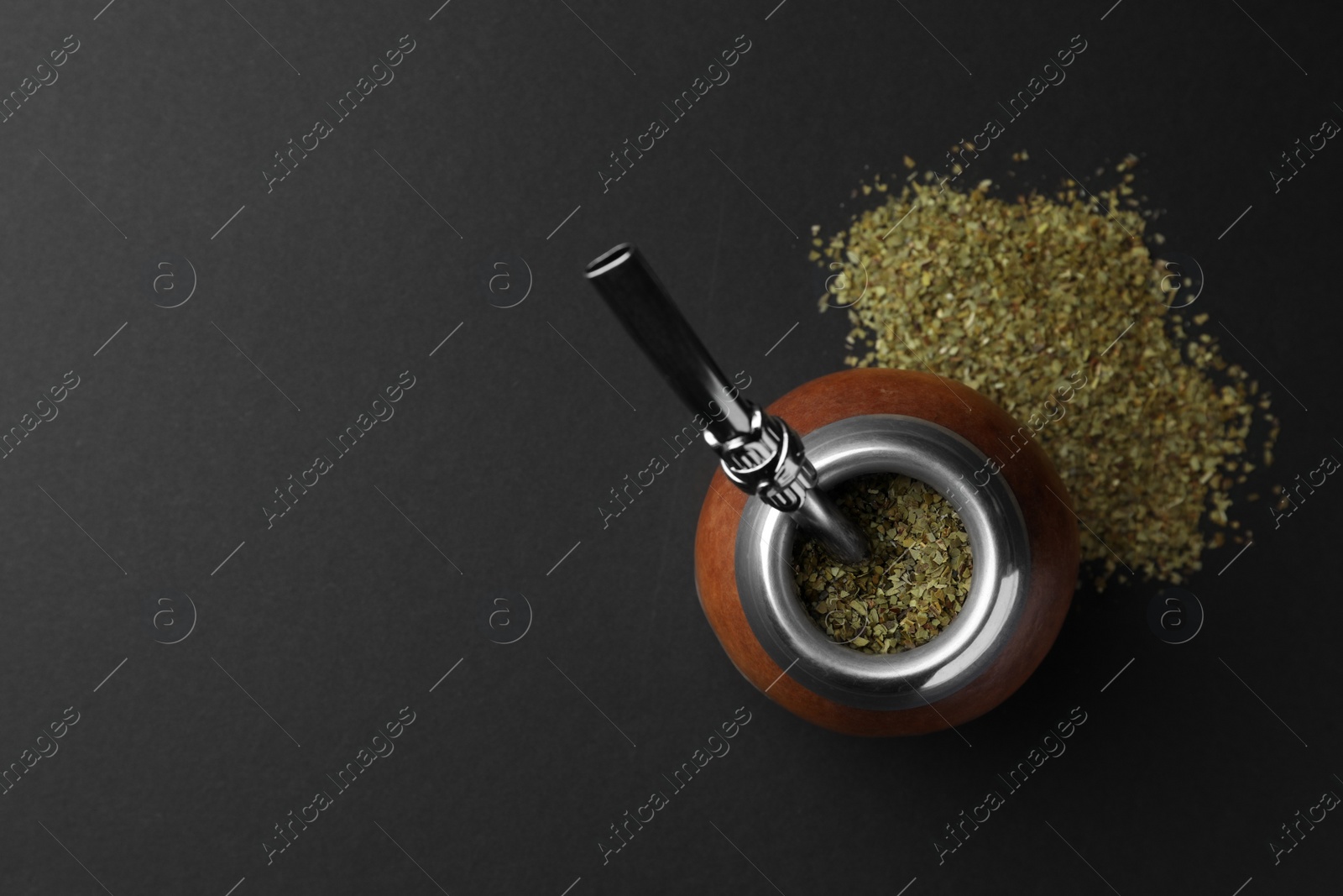 Photo of Calabash with mate tea and bombilla on black table, flat lay. Space for text