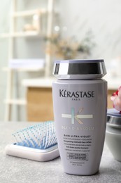 Photo of MYKOLAIV, UKRAINE - SEPTEMBER 07, 2021: Kerastase shampoo and hair brush on light table in bathroom