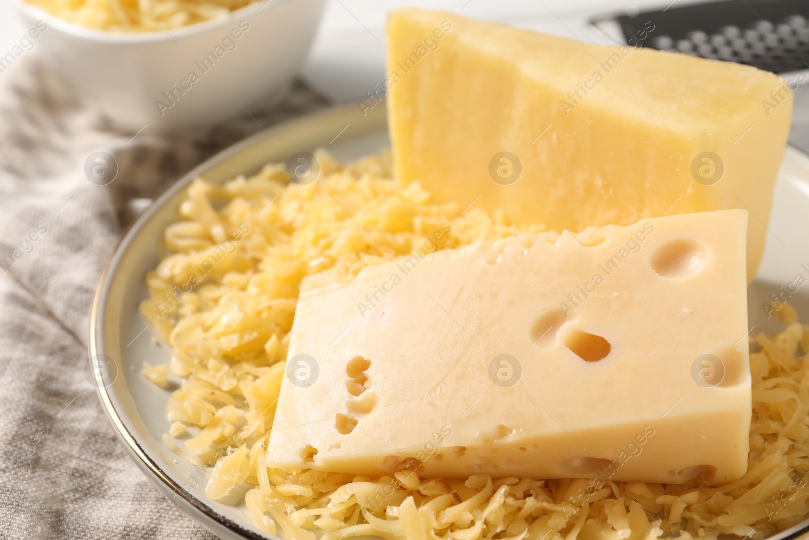 Photo of Grated and whole pieces of cheese on cloth, closeup