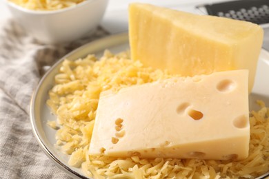 Photo of Grated and whole pieces of cheese on cloth, closeup