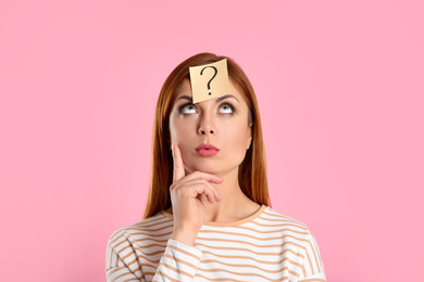 Photo of Emotional woman with question mark sticker on forehead against pink background