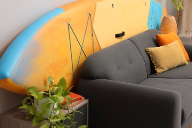 Closeup view of SUP board behind stylish sofa in room. Interior element