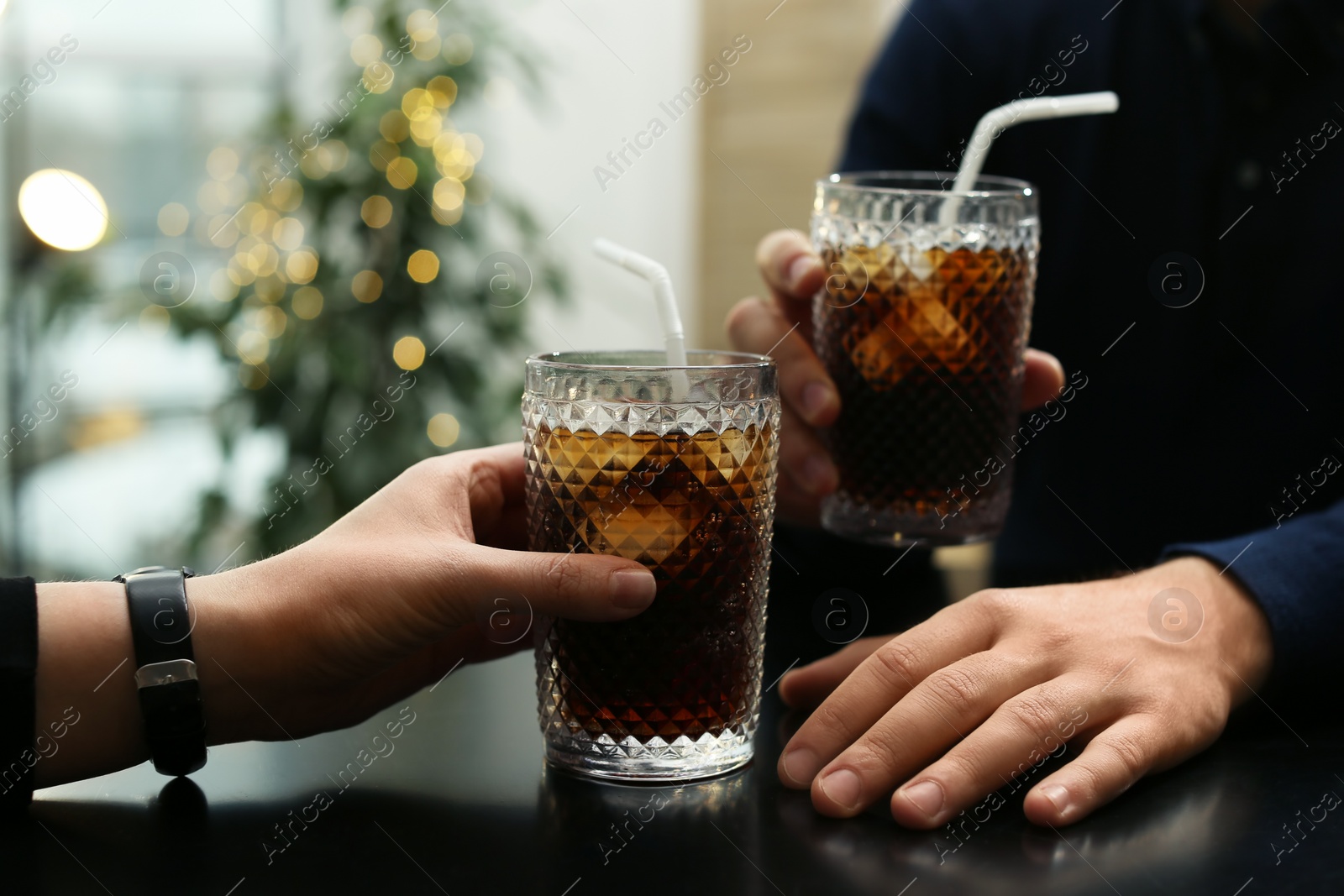 Photo of Couple with glasses of cold cola at table in cafe, closeup