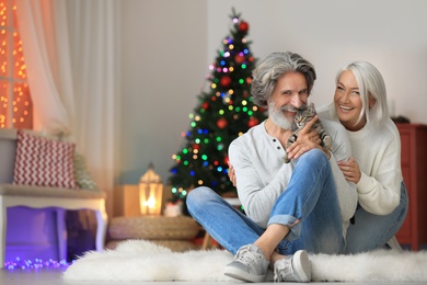 Photo of Happy couple with cute cat celebrating Christmas at home