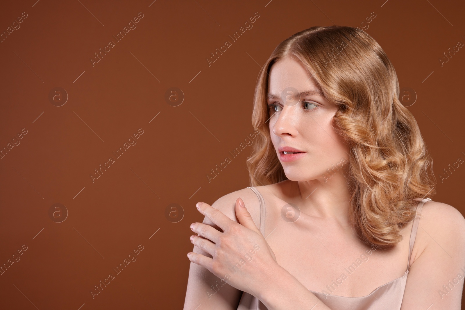 Photo of Portrait of beautiful woman with blonde hair on brown background. Space for text