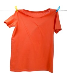 One orange t-shirt drying on washing line isolated on white