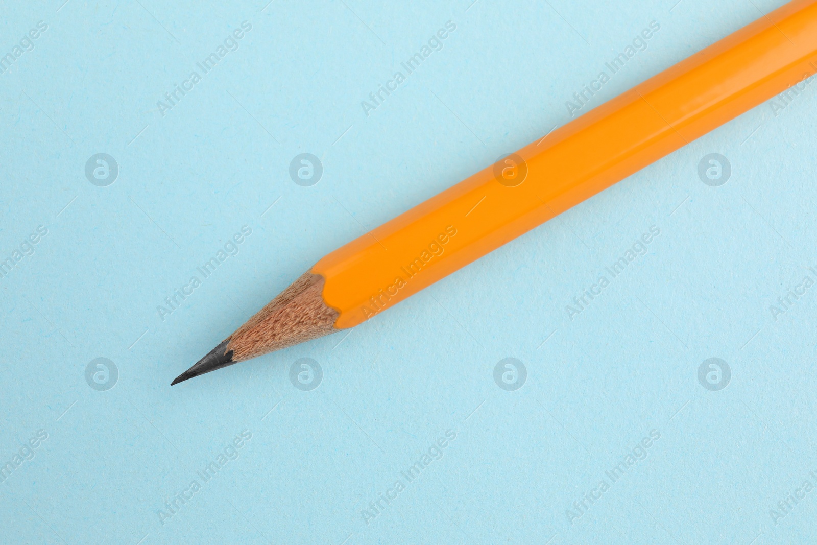 Photo of One sharp graphite pencil on light blue background, top view