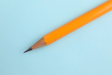 Photo of One sharp graphite pencil on light blue background, top view