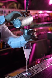 Bartender making fresh alcoholic cocktail at counter in bar, closeup