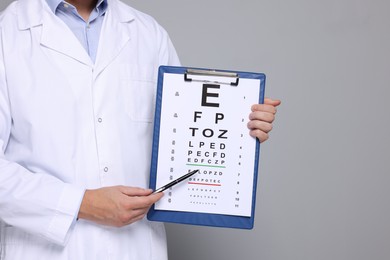 Photo of Ophthalmologist pointing at vision test chart on gray background, closeup