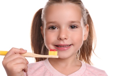 Little girl holding toothbrush with paste on white background