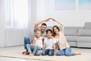 Photo of Happy family forming house roof with their hands at home. Insurance concept