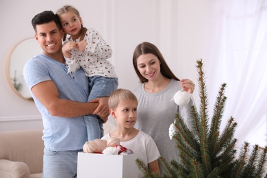 Photo of Happy family with cute children decorating Christmas tree together at home