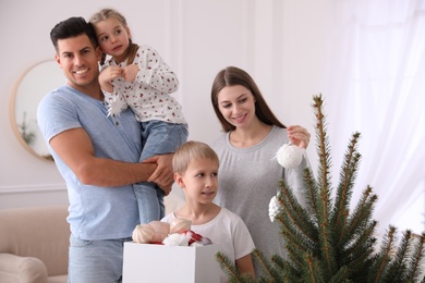 Happy family with cute children decorating Christmas tree together at home