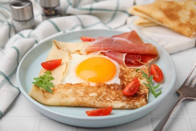 Photo of Delicious crepe with egg served on white tiled table, closeup. Breton galette