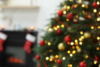 Photo of Beautiful Christmas tree near fireplace indoors, blurred view