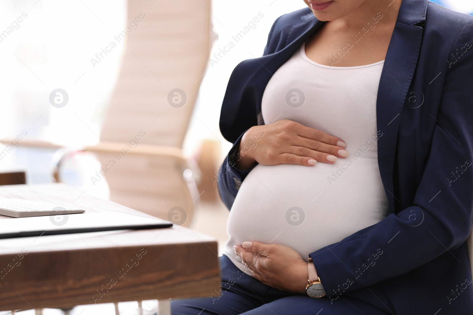 Photo of Young pregnant woman in suit at workplace, closeup. Space for text