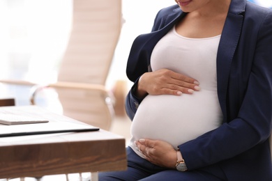 Photo of Young pregnant woman in suit at workplace, closeup. Space for text