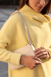 Fashionable young woman with stylish bag on city street, closeup