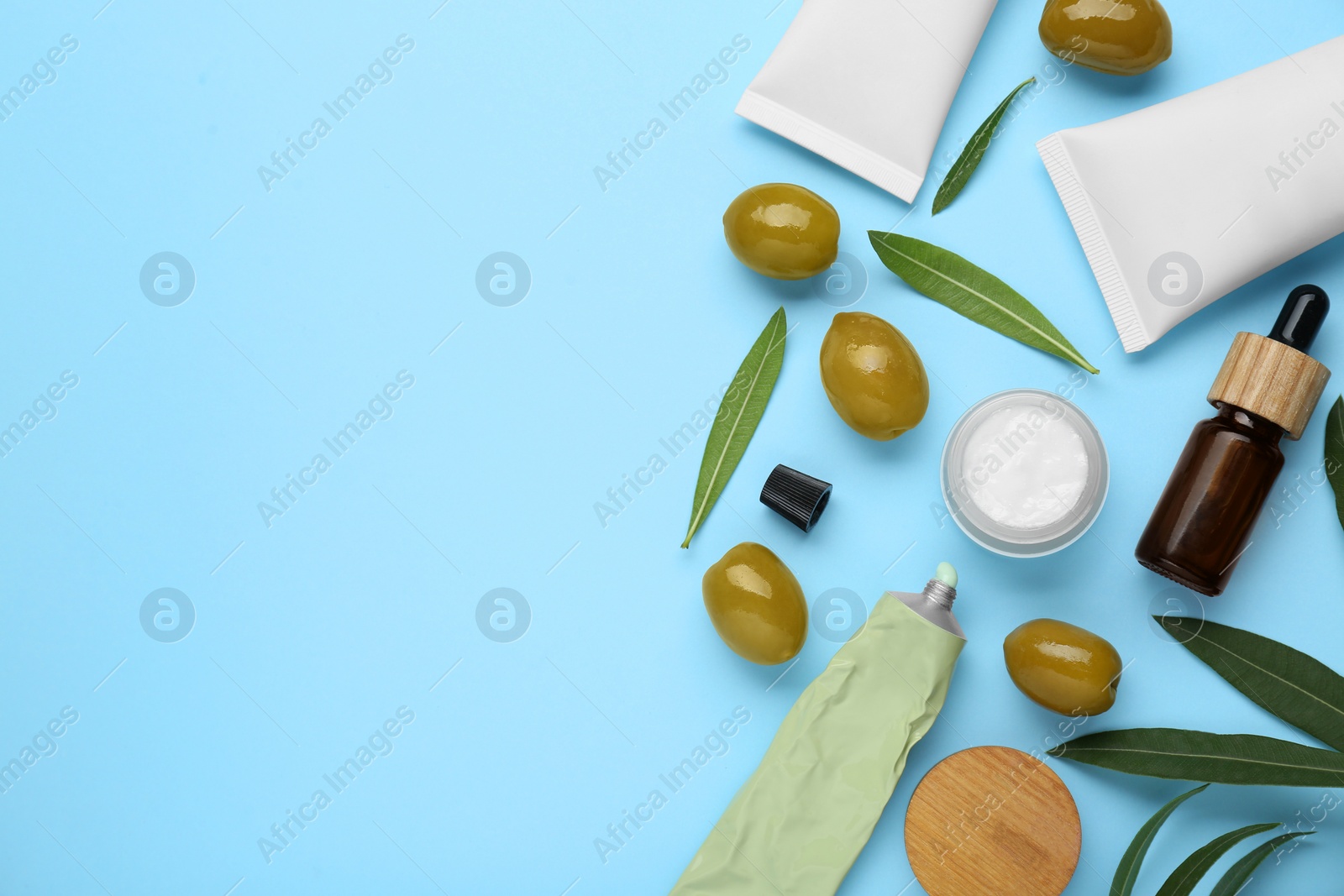 Photo of Cosmetic products with olive essential oil light turquoise background, flat lay. Space for text