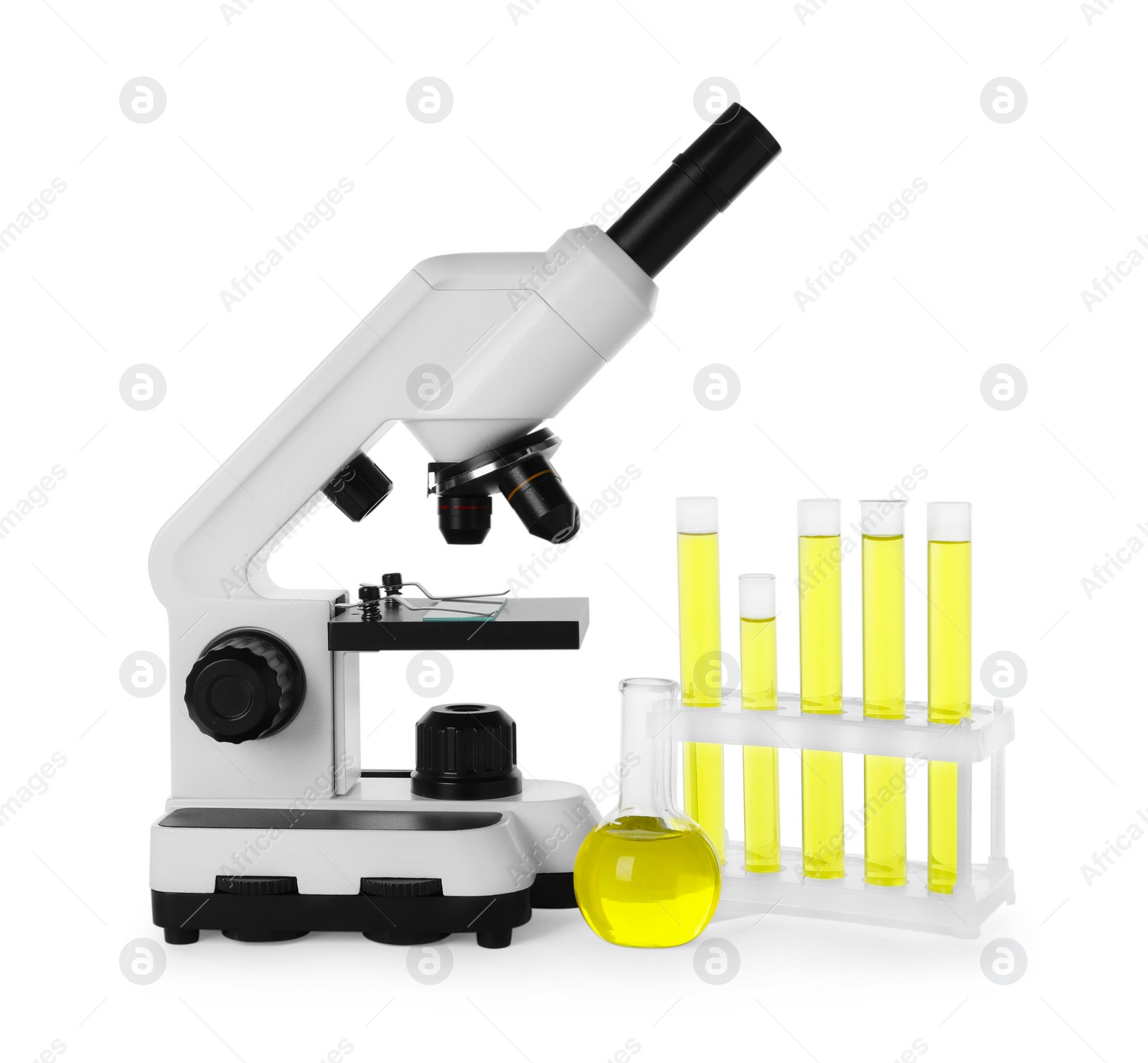 Photo of Laboratory glassware with yellow liquid and microscope isolated on white