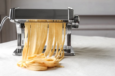 Pasta maker with wheat dough on table