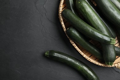 Photo of Basket with green zucchinis on black slate table, flat lay. Space for text