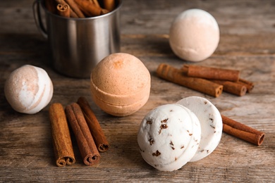 Photo of Bath bombs with cinnamon sticks on wooden table