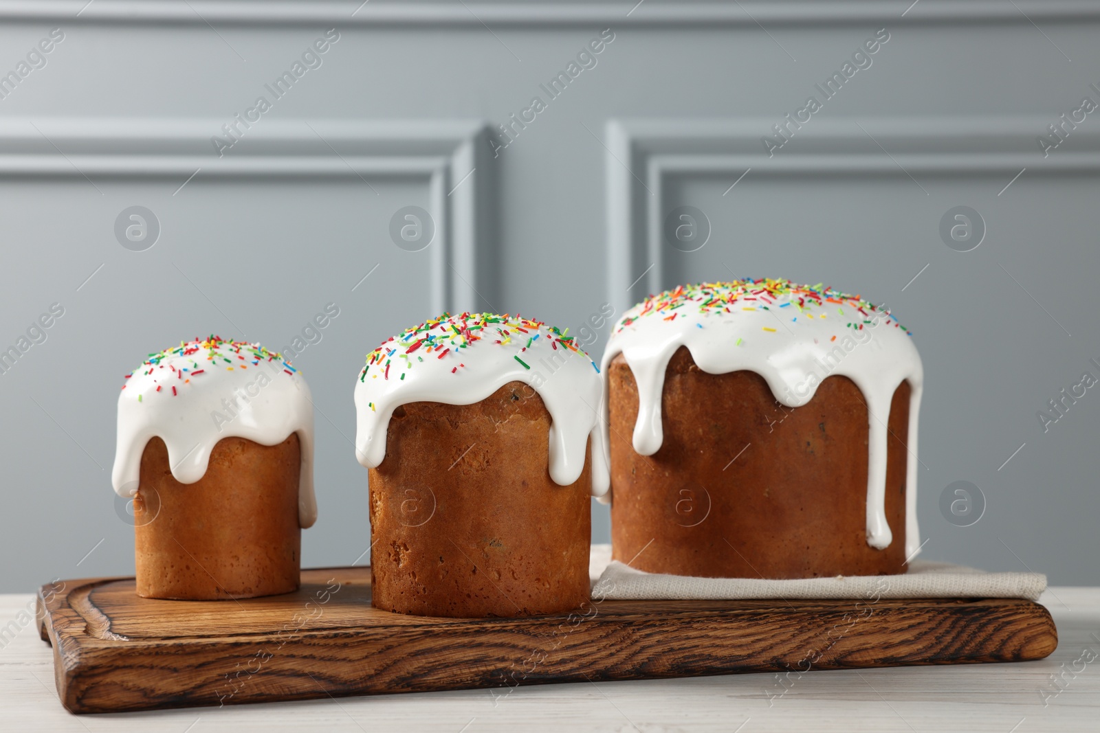 Photo of Delicious Easter cakes with sprinkles on white wooden table near light grey wall indoors